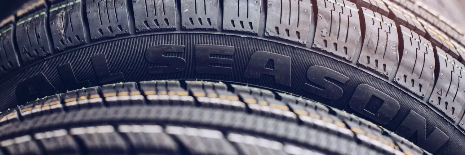 Close-up shot of two stacked tires with the text ALL SEASON prominently visible on the surface of one tire. The tire treads are detailed, highlighting the textured pattern designed for enhanced grip. Superior Tire: Tire Shop and Auto Repair Near Me | Barrie | Danforth | Downsview | Markham | Mississauga | Oak Ridges | Scarborough | Thornhill | Toronto | https://superiortire.ca/
