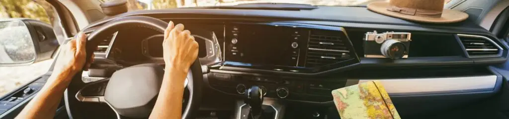 Close-up of a person driving a car, hands on the steering wheel, ready for adventure. The dashboard sports a vintage camera and a hat. A colorful map rests on the passenger seat, just in case they need to detour for a quick tire change nearby as sunlight streams through the window warmly. Superior Tire: Tire Shop and Auto Repair Near Me | Barrie | Danforth | Downsview | Markham | Mississauga | Oak Ridges | Scarborough | Thornhill | Toronto | https://superiortire.ca/