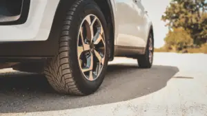 Replace two tires or all four? Technician measuring tire tread depth before replacement